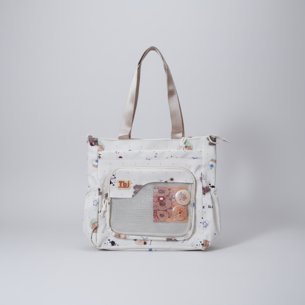 A white fabric tote bag with a cute multicolor cartoon bear print, featuring dual shoulder straps, a front zippered pocket, and a mesh window holding a decorative card.