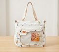 Cream canvas tote bag with cute bear and star print, front mesh pocket, and leather-look badge detail